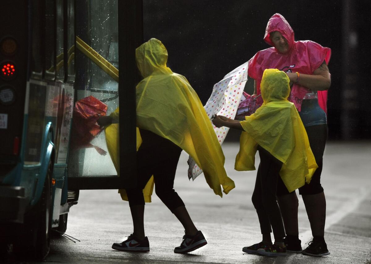 Rain pelts a woman and two girls as they board a bus during an early morning thunder storm in Vista. Unusual weather brought lightning, hail and rain to a wide portion of Southern California.