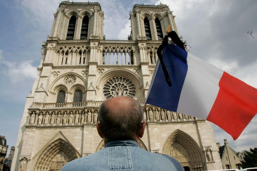 Mandatory Credit: Photo by LUCAS DOLEGA/EPA-EFE/REX (10205152a) (FILE) - A man stands with the French Flag in front of Notre Dame Cathedral in Paris, France, 03 June 2009 (reissued 15 April 2019). A fire started in the late afternoon on 15 April 2019 at the roof of Notre Dame, one of the most visited monuments of the French capital. Cathedral of Notre-Dame of Paris on fire, France - 03 Jun 2009 ** Usable by LA, CT and MoD ONLY **