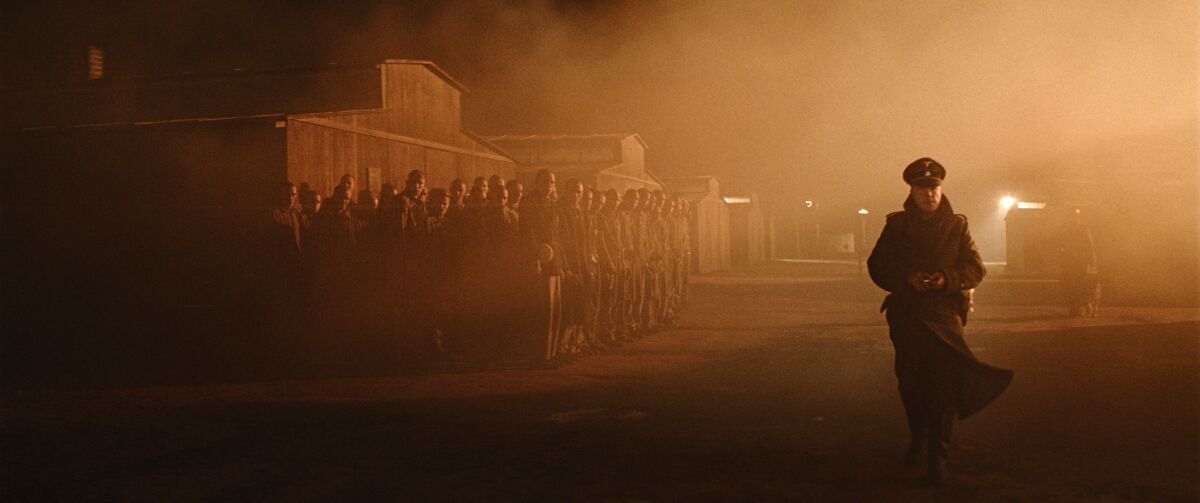 A Nazi officer walks past prisoners in a World War II concentration camp in the movie “The Auschwitz Report.”