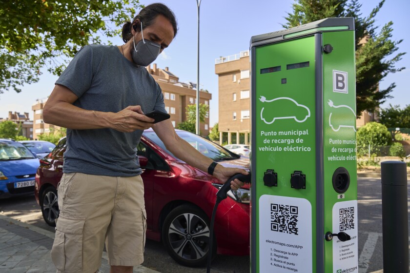 A man charges his electric car at an electrical charging point in Rivas Vaciamadrid, Spain, Tuesday, June 15, 2021. Spain is Europe's second-leading car maker but it is lagging behind when it comes to electric cars, a situation that the government aims to change by using around five billion euros of the EU pandemic recovery funds to kickstart the electric car industry. The government plans to spend big, to install a network of public recharging stations and to convince customers about the benefits of buying electric or hybrid vehicles. (AP Photo/Manu Fernandez)