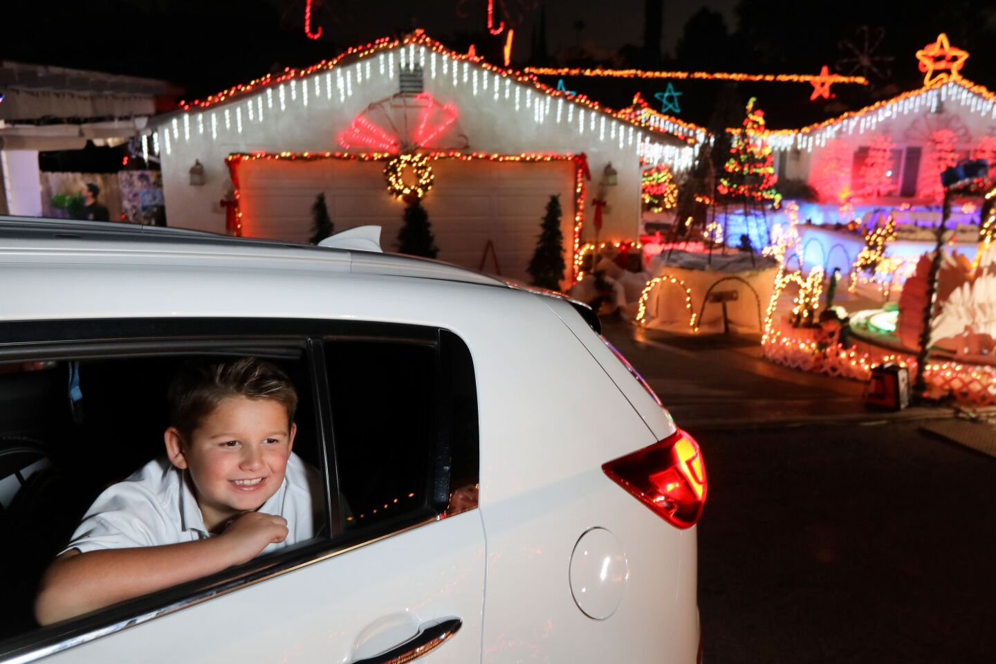 Eight-year-old Logan Taylor enjoys the extensive Christmas decorations on both side of the circular driveway of the home of Mack Schreiber on Reche Road in Fallbrook. A steady stream of vehicles pass through.