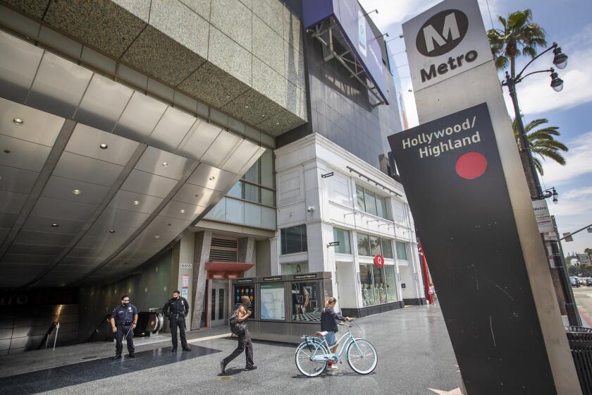 HOLLYWOOD, CA - JUNE 25: LAPD officers E. Rosales, left, and D. Castro, patrol the Metro Red Line Hollywood/Highland Metro Station as pedestrians pass by Thursday, June 25, 2020 in Hollywood, CA. The Metro Board of Directors held a meeting Thursday where the agenda included the consideration of appointing a committee to develop plans for replacing armed transit safety officers with ``smarter and more effective methods of providing public safety.'' Metro security is staffed by multiple agencies, including the L.A. County Sheriff's Department and L.A. and Long Beach police departments, transit security guards and contract security workers. (Allen J. Schaben / Los Angeles Times)