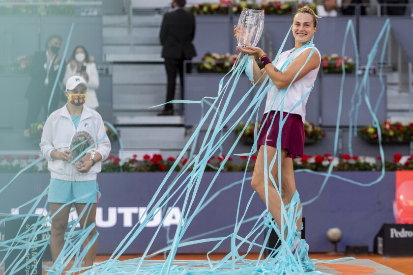 Aryna Sabalenka of Belarus, right, holds a trophy after winning the women's final match against Australia's Ashleigh Barty at the Mutua Madrid Open tennis tournament in Madrid, Spain, Saturday, May 8, 2021. (AP Photo/Bernat Armangue)