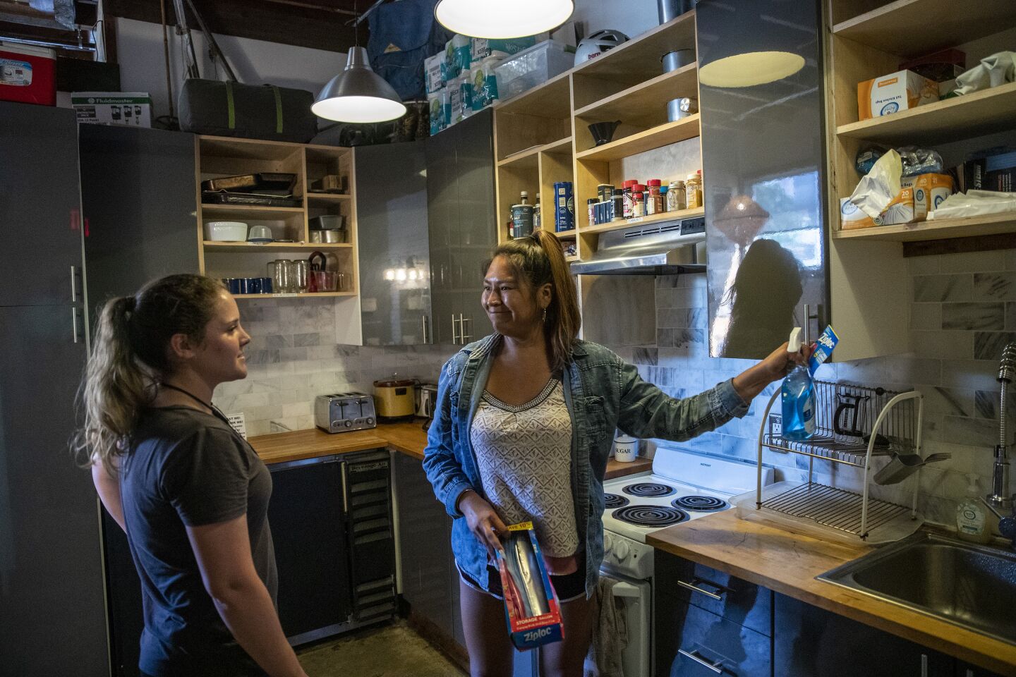 LOS ANGELES, CALIF. -- FRIDAY, OCTOBER 4, 2019: German tourist Lilly Geyer, 22, left, chats with front desk receptionist Blosson Manuel, right, in the common kitchen at PodShare Los Feliz in Los Angeles, Calif., on Oct. 4, 2019. (Brian van der Brug / Los Angeles Times)