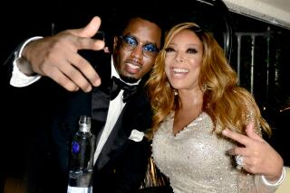 Sean "Diddy" Combs in a tuxedo posing next to Wendy Williams in a gold dress at a New Year's party