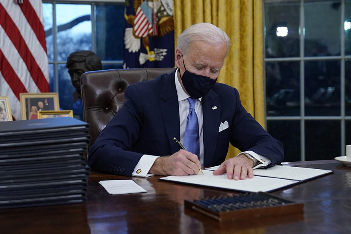 President Biden signs his first executive orders in the Oval Office on Jan. 20.