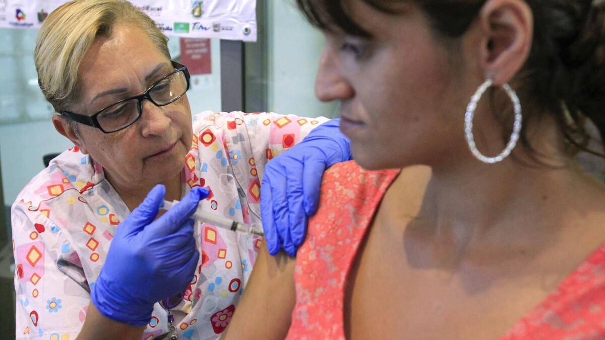 Maria Baeza, RN, gives Roxanne Flores a flu shot at a table set up for free vaccinations at the County of San Diego South Region Live Well Center in Chula Vista on Thursday.
