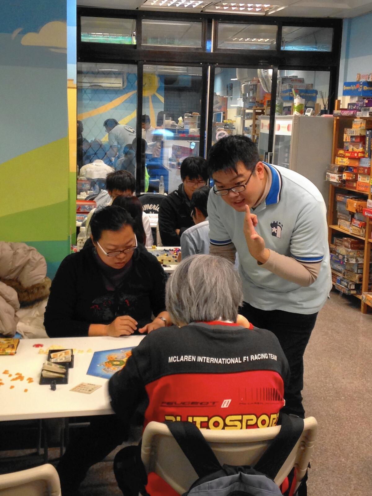 Lo Kuei-hua, manager of a Taipei board game parlor, shows customers how to play one of the 200 games he has in stock.