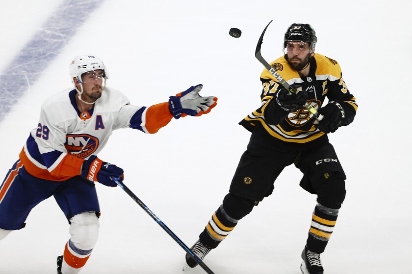 Boston Bruins' Patrice Bergeron and New York Islanders' Brock Nelson go for a loose puck in the second period of Game 2 during an NHL hockey second-round playoff series, Monday, May 31, 2021, in Boston. (AP Photo/Winslow Townson)