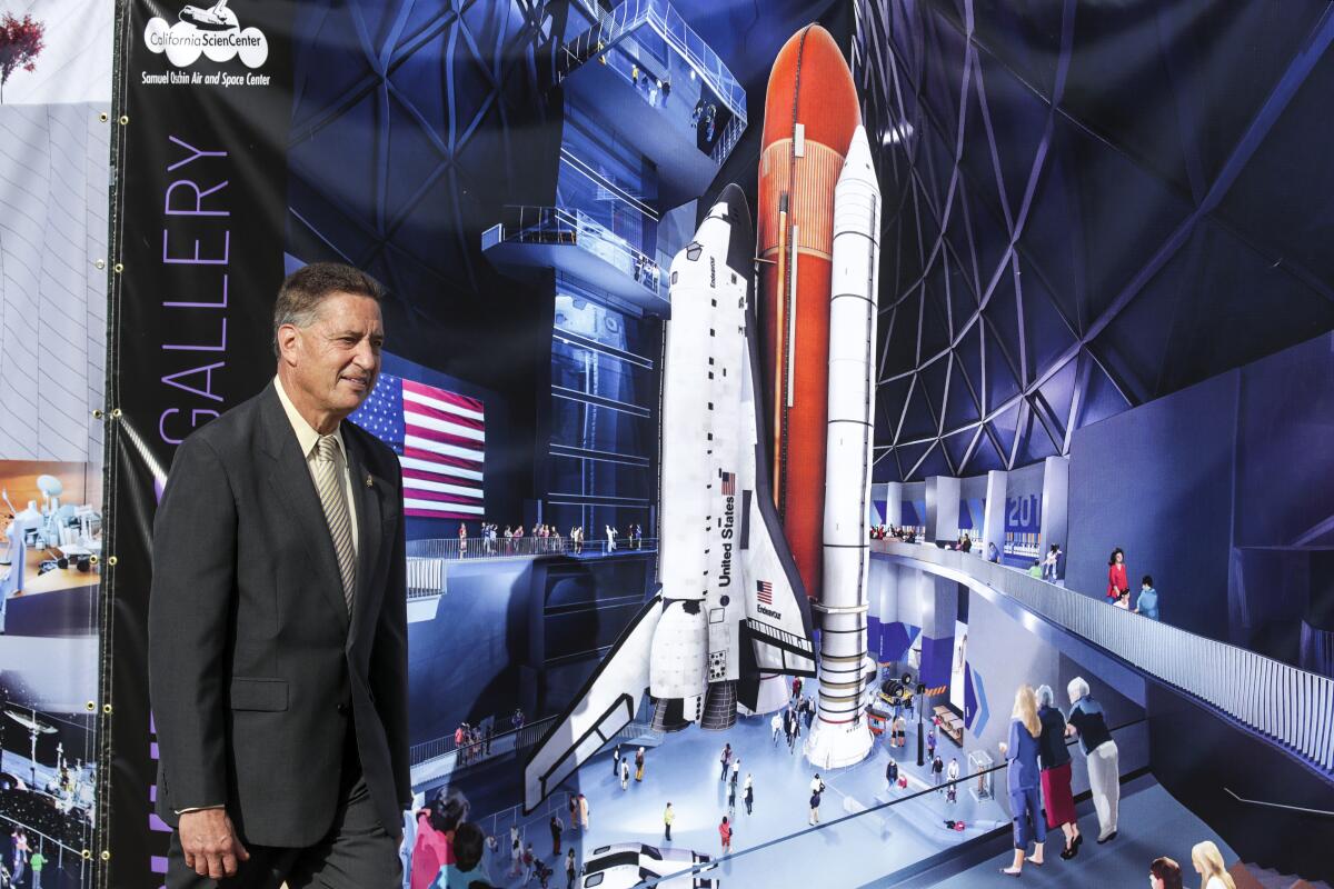 A man stands next to a rendering of a space shuttle exhibit.