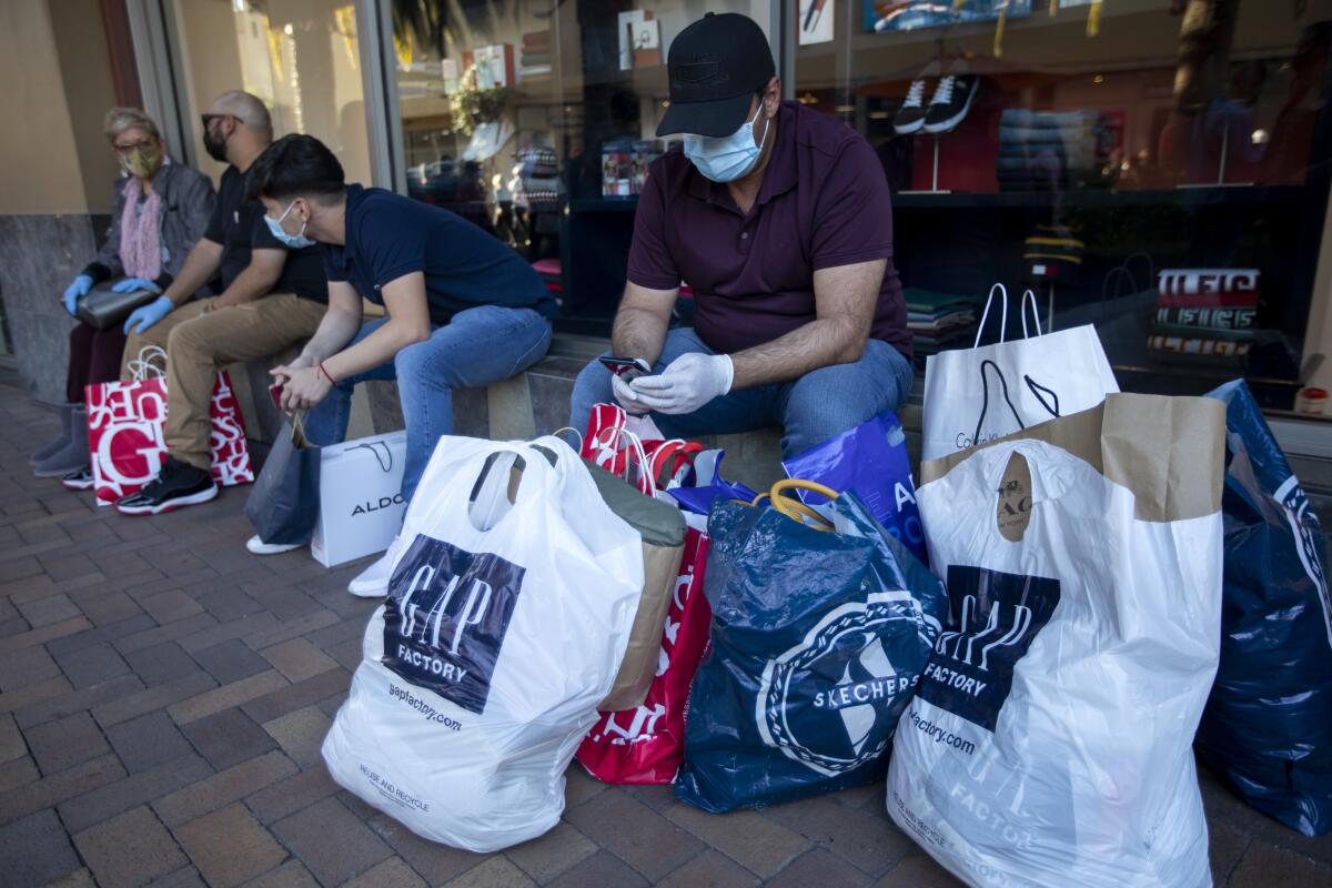 Shoppers wait with their bags at the Citadel Outlets in Commerce on Nov. 28.