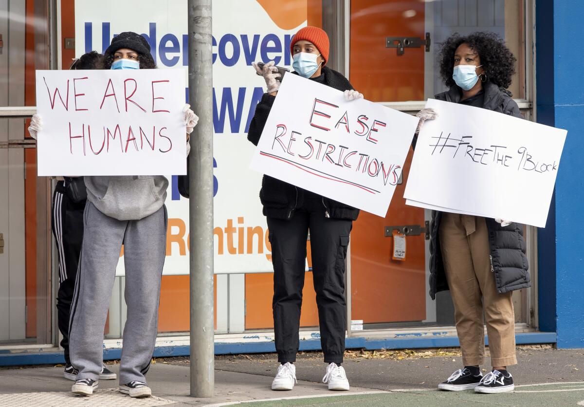 Women hold signs about coronavirus restrictions in Melbourne, Australia