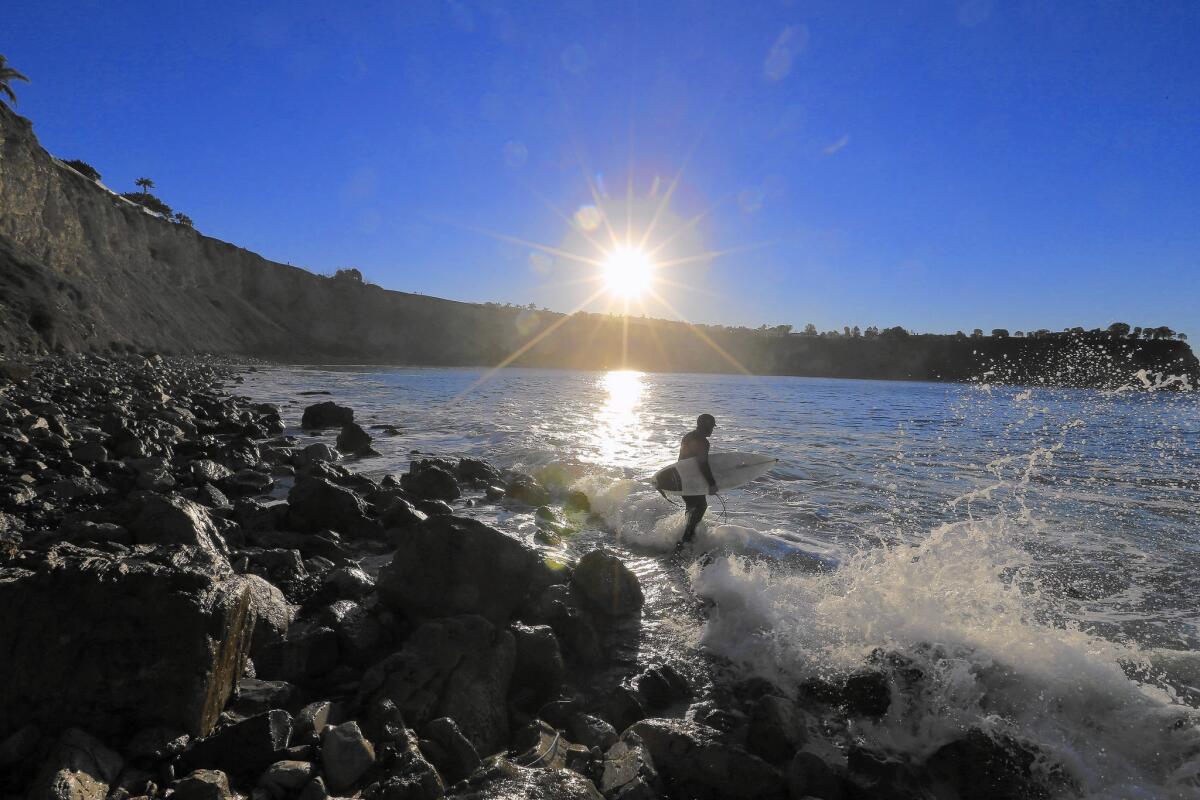 With police watching from the bluff, a surfer heads out at Lunada Bay with a small group of fellow outsiders in February, a challenge to the "Bay Boys," who are accused of using intimidation to keep the spot to themselves.