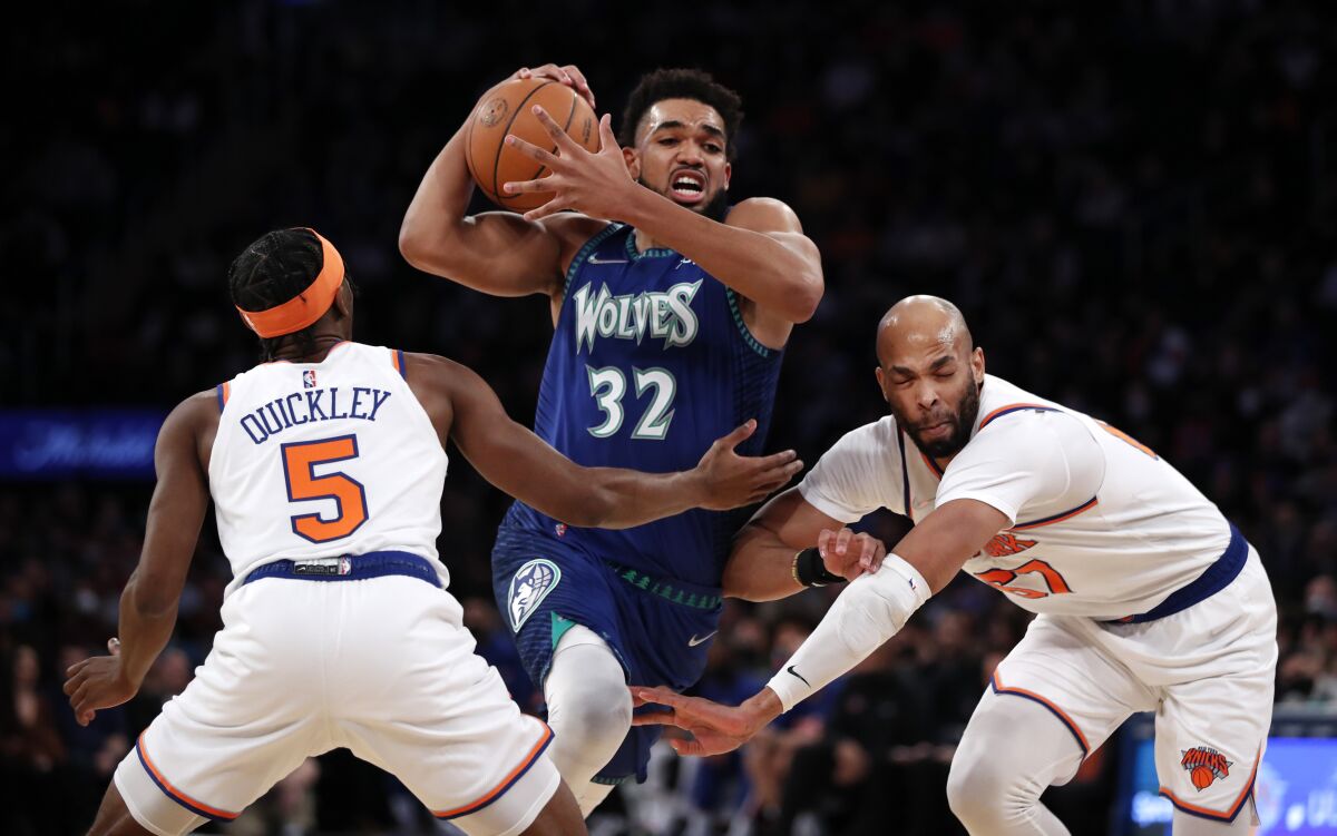Minnesota Timberwolves center Karl-Anthony Towns (32) drives to the basket against New York Knicks guard Immanuel Quickley (5) and New York Knicks center Taj Gibson (67) during the first half of an NBA basketball game, Tuesday, Jan. 18, 2022 in New York. (AP Photo/Noah K. Murray)