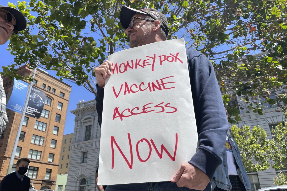 Un hombre sostiene un letrero en el que pide acceso a la vacuna contra la viruela símica 