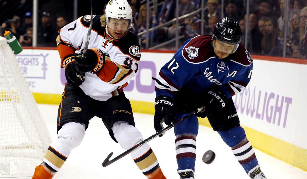 Ducks defenseman Hampus Lindholm, left, clears the puck from behind the net against Avalanche right wing Jarome Iginla in the third period Sunday in Denver.