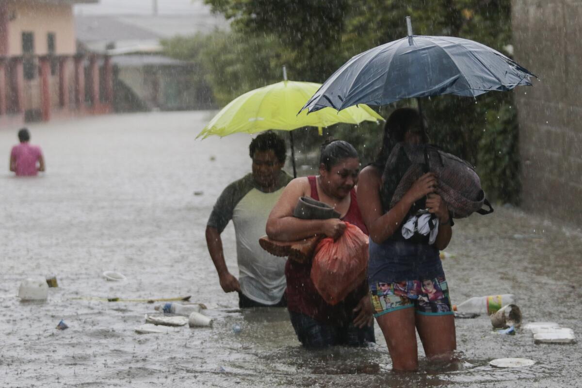 Residentes caminan por una carretera inundada con algunas pertenencias en Progreso Yoro, Honduras