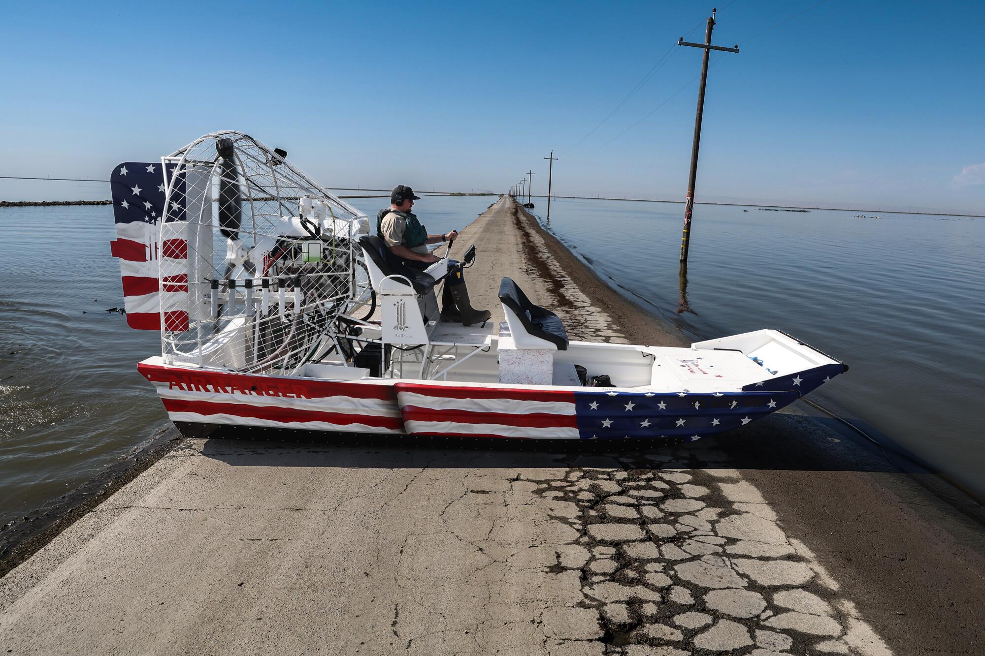 Sheriff's deputies tour Tulare Lake in a red, white and blue airboat.