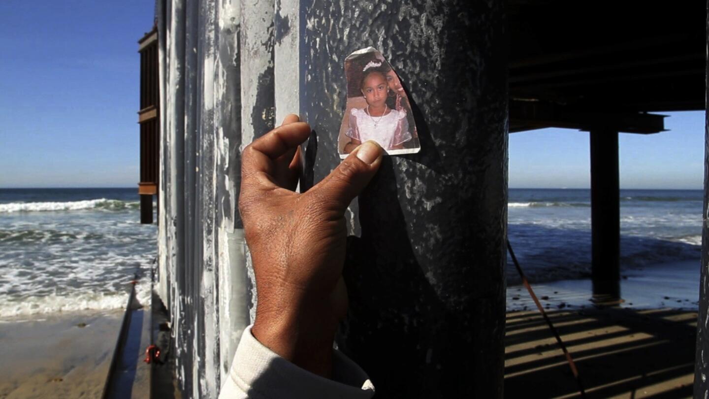 On the Tijuana side of the border fence, Luis Ernesto Rodriguez, 43, holds up a tattered snapshot of one of his young daughters. He was here when one of his attorneys delivered news about his long fight to be reunited with them.