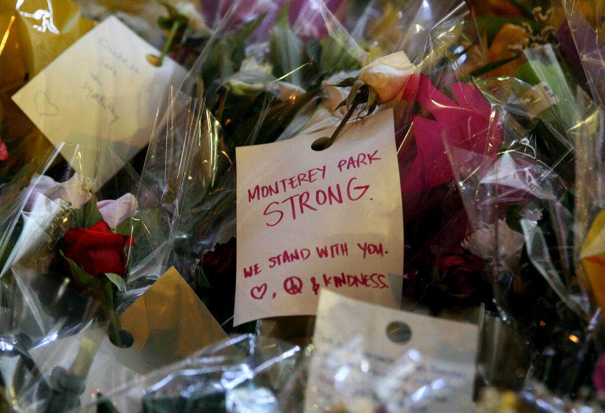 A note is attached to flowers left for the 11 shooting victims in front of Star Ballroom Dance Studio in Monterey Park.