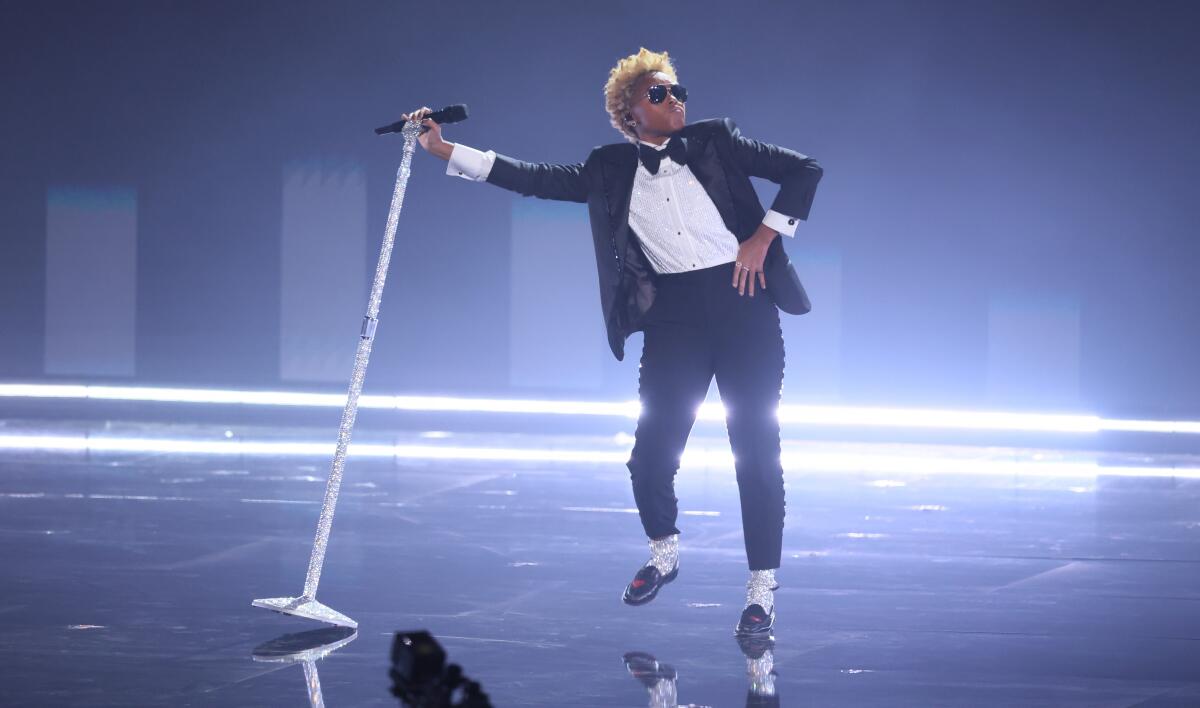 Janelle Monáe, dressed like "Off the Wall"-era Michael Jackson, at a microphone onstage.