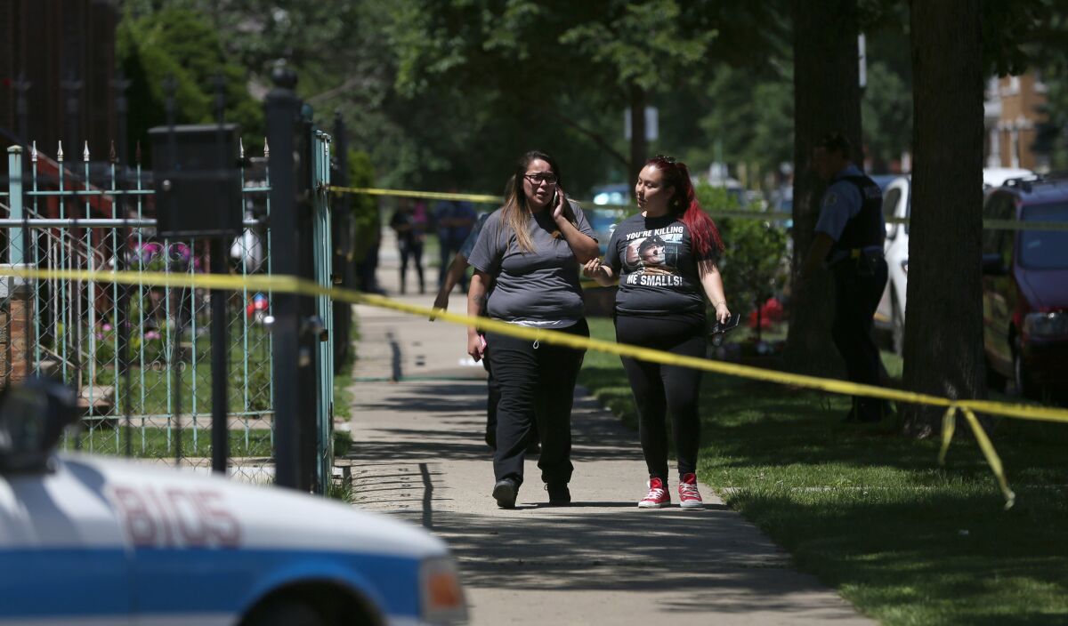Relatives of the father who was shot talk on the phone at the crime scene on Thursday.
