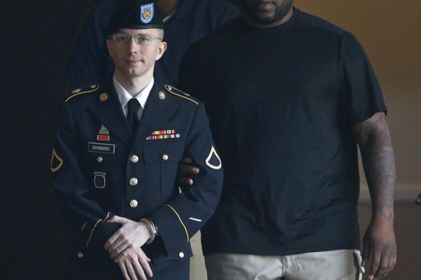 Army Pfc. Bradley Manning is escorted to a waiting security vehicle outside of a courthouse in Fort Meade, Md. after appearing for a hearing at his court martial.