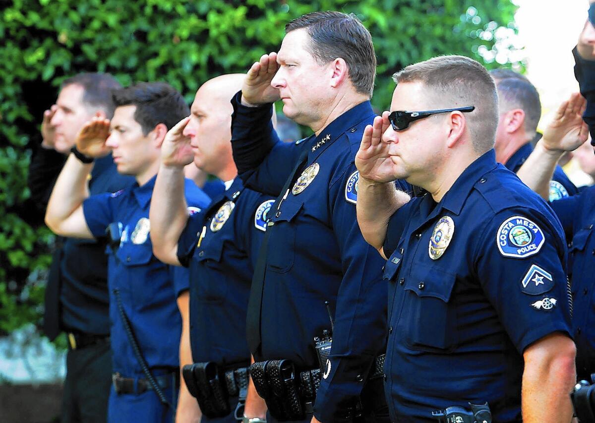 Costa Mesa Police Chief Rob Sharpnack, second from right, salutes with members of Costa Mesa Police and Fire departments during a Patriot Day remembrance ceremony Friday at City Hall.