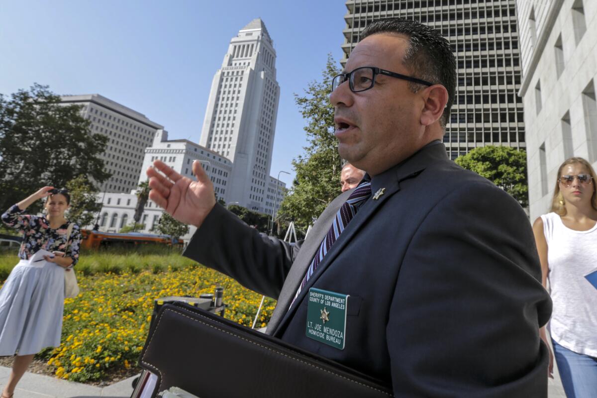 Lt. Joe Mendoza gesturing as he speaks, with L.A. City Hall in the background
