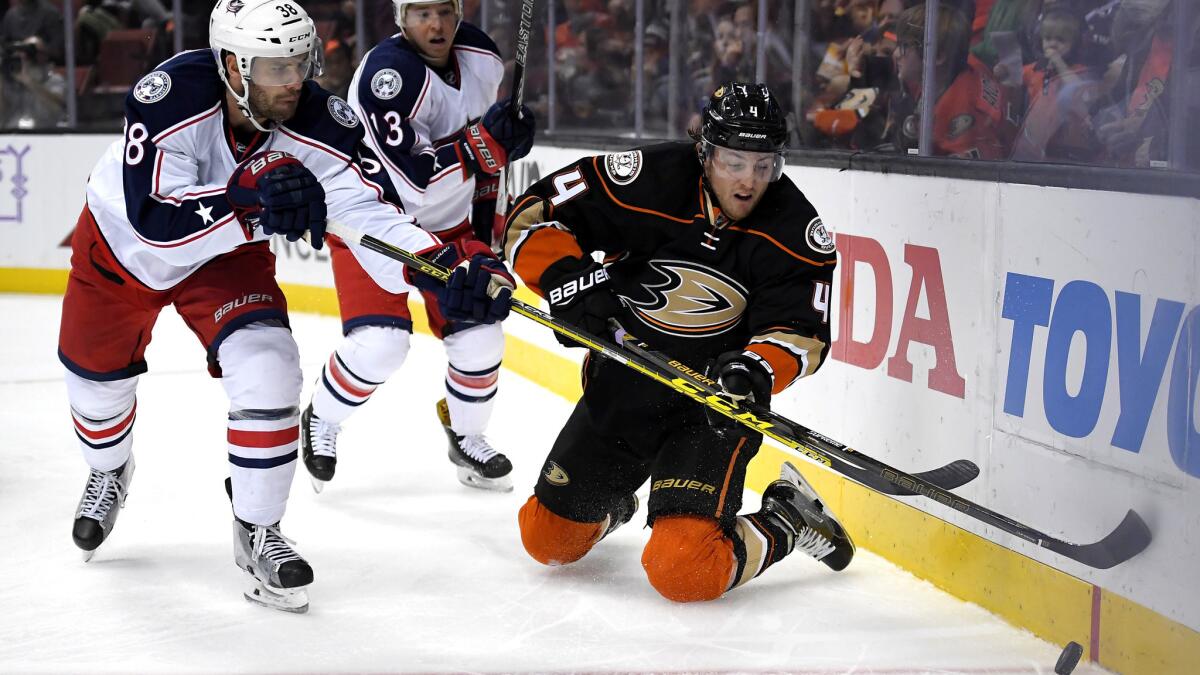 Ducks defenseman Cam Fowler (4) tries to clear the puck under pressure from Blue Jackets center Boone Jenner, left, during a game Oct. 28 at Honda Center.