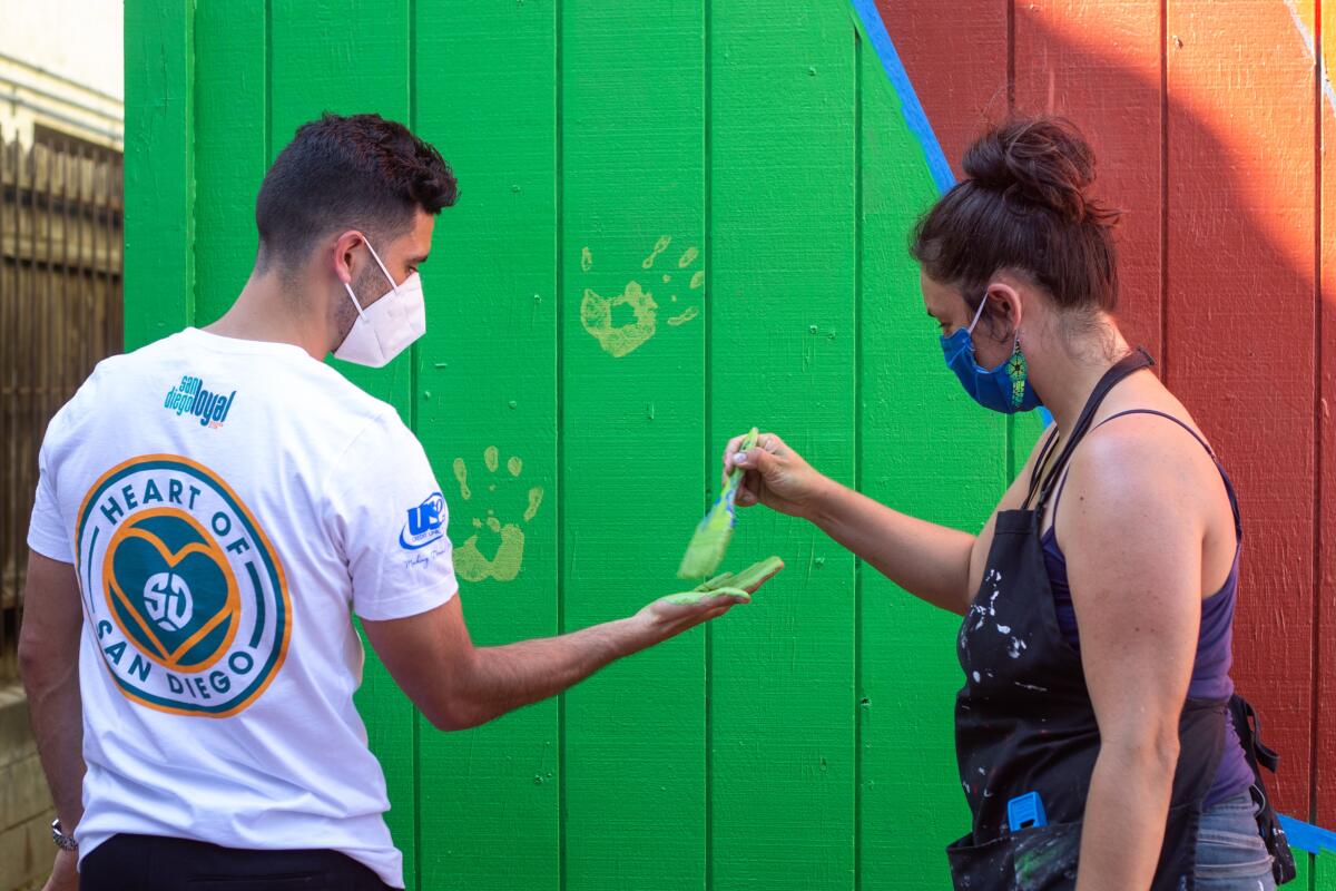 El futbolista Alejandro Guido junto a la artista Yessenia Hulsey en el mural comunitario en Delta Apartments