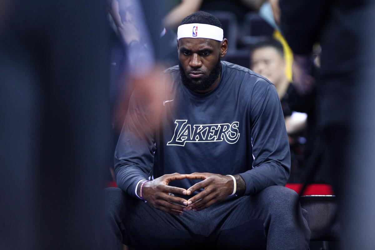 Lakers star LeBron James sits on the bench before an exhibition game against the Brooklyn Nets in China on Oct. 12.
