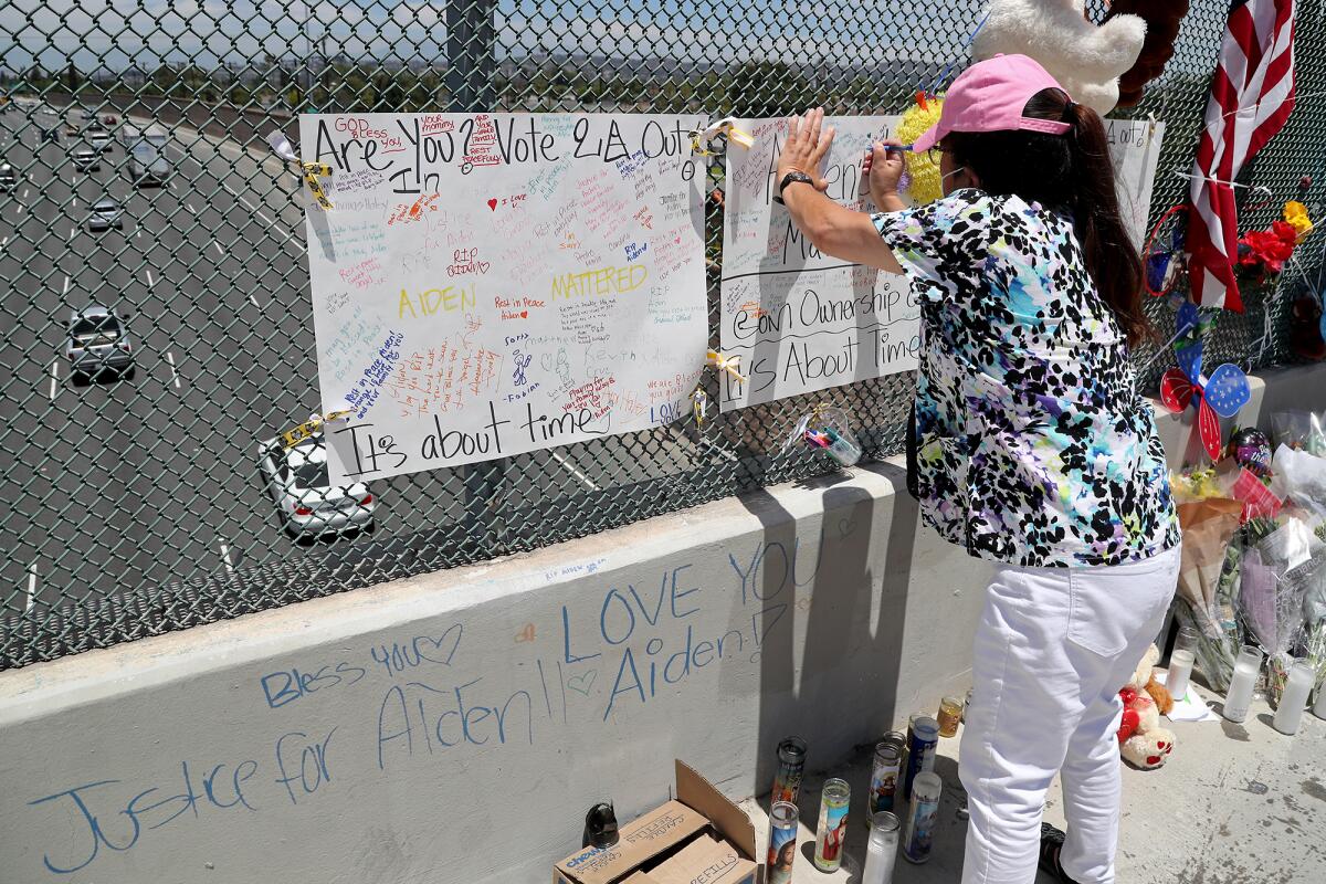 Patricia Alkawadri of Santa Ana leaves a message at a makeshift memorial for 6-year-old Aiden Leos of Costa Mesa. 