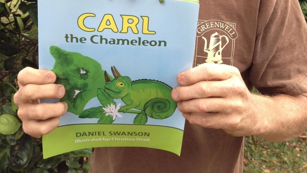 Author Daniel Swanson holds a copy of his first children's book, a work of fiction about the very real "Carl the Chameleon." (Greenwell Farms)
