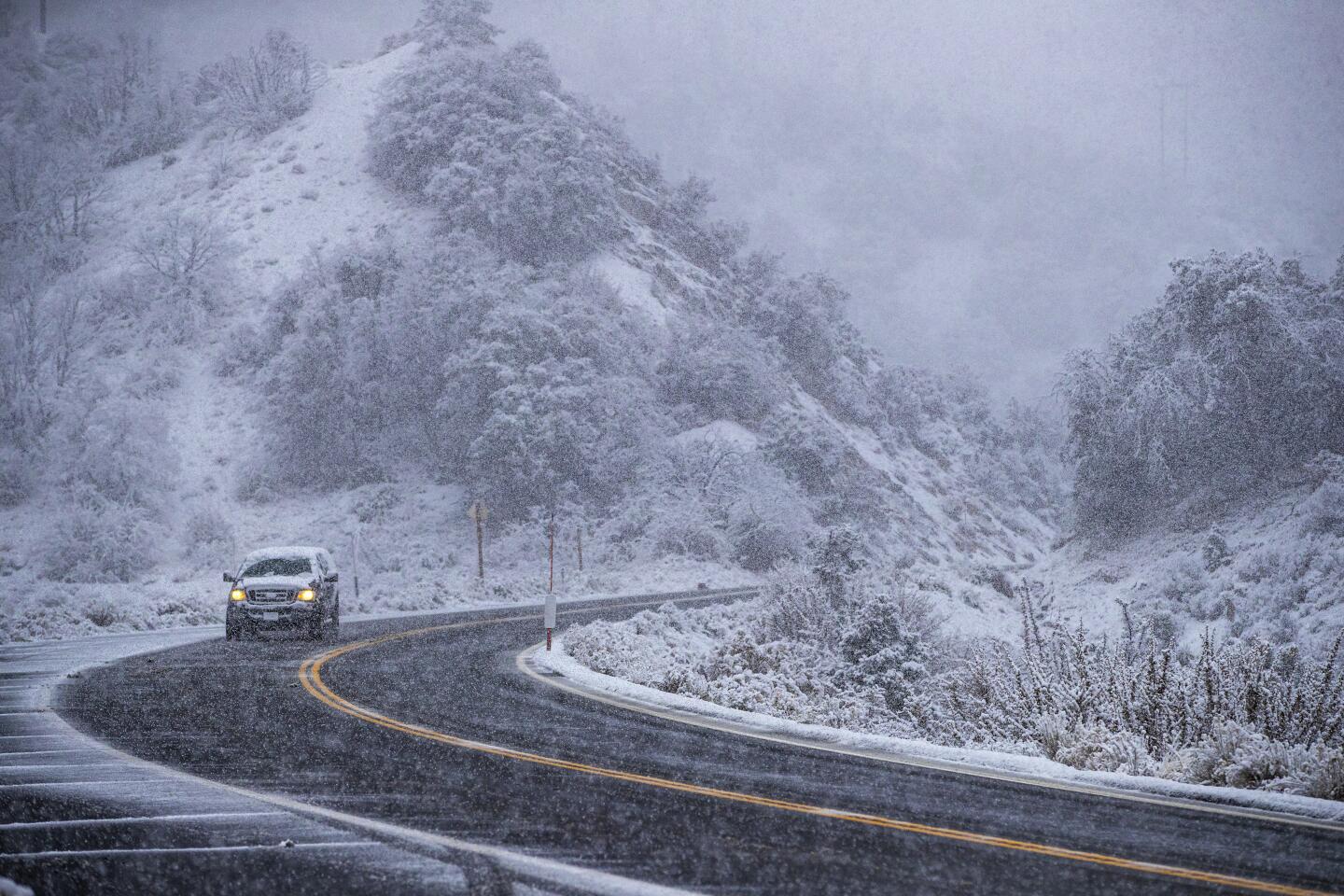 Snow blankets high-desert plant life and terrain along Highway 2 as the first snowfall of the season arrives in Wrightwood, California.