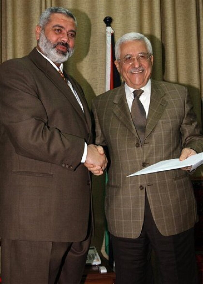 FILE - In this Sunday, March 19, 2006 file photo made available by the Palestinian Authority, the Palestinian Authority President Mahmoud Abbas, right, holds a file with the proposal for a new Palestinian Cabinet as he shakes hands with Palestinian Prime Minister Ismail Haniyeh, from the Islamic group Hamas, in Gaza City. Hamas officials said Tuesday, May 3, 2011, that the Islamic militant group would honor an unofficial truce with Israel after forming a new government with Palestinian rivals from the West Bank. (AP Photo/Abdel Alahim Abu Askar/Palestinian Authority, File)