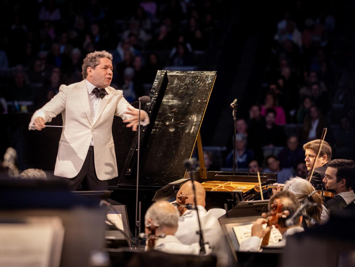 Gustavo Dudamel conducts in white suit.
