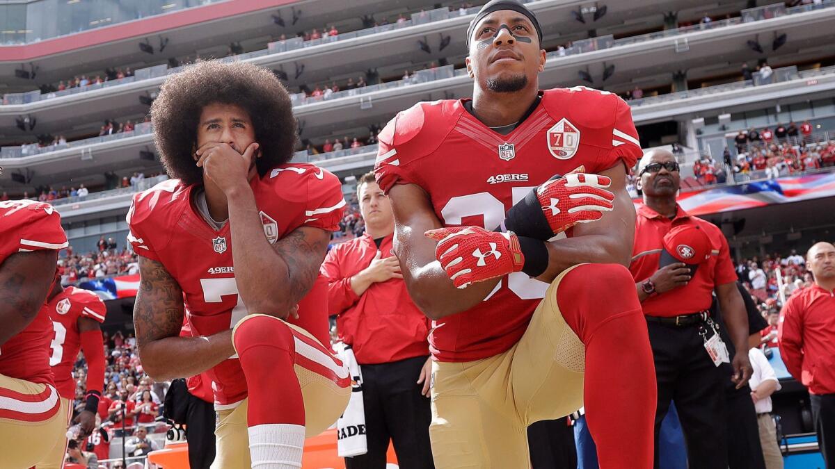 Then-49ers quarterback Colin Kaepernick and safety Eric Reid kneel during the national anthem before an NFL game in 2016.