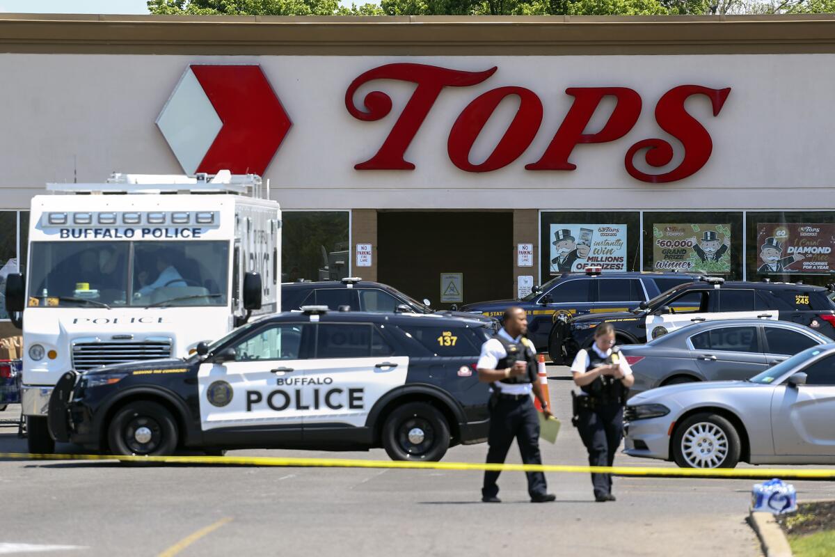 FILE — Police walk outside the Tops grocery store May 15, 2022, in Buffalo, N.Y. The white gunman charged with killing 10 Black people in a racist mass shooting at a Buffalo supermarket is scheduled for arraignment in federal court on Monday, July 18, 2022, on an indictment that could make him eligible for the death penalty if he is found guilty. (AP Photo/Joshua Bessex, File)