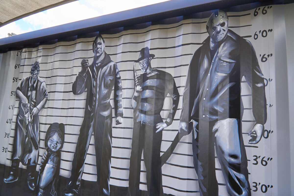 A black-and-white mural shows a collection of movie villains.