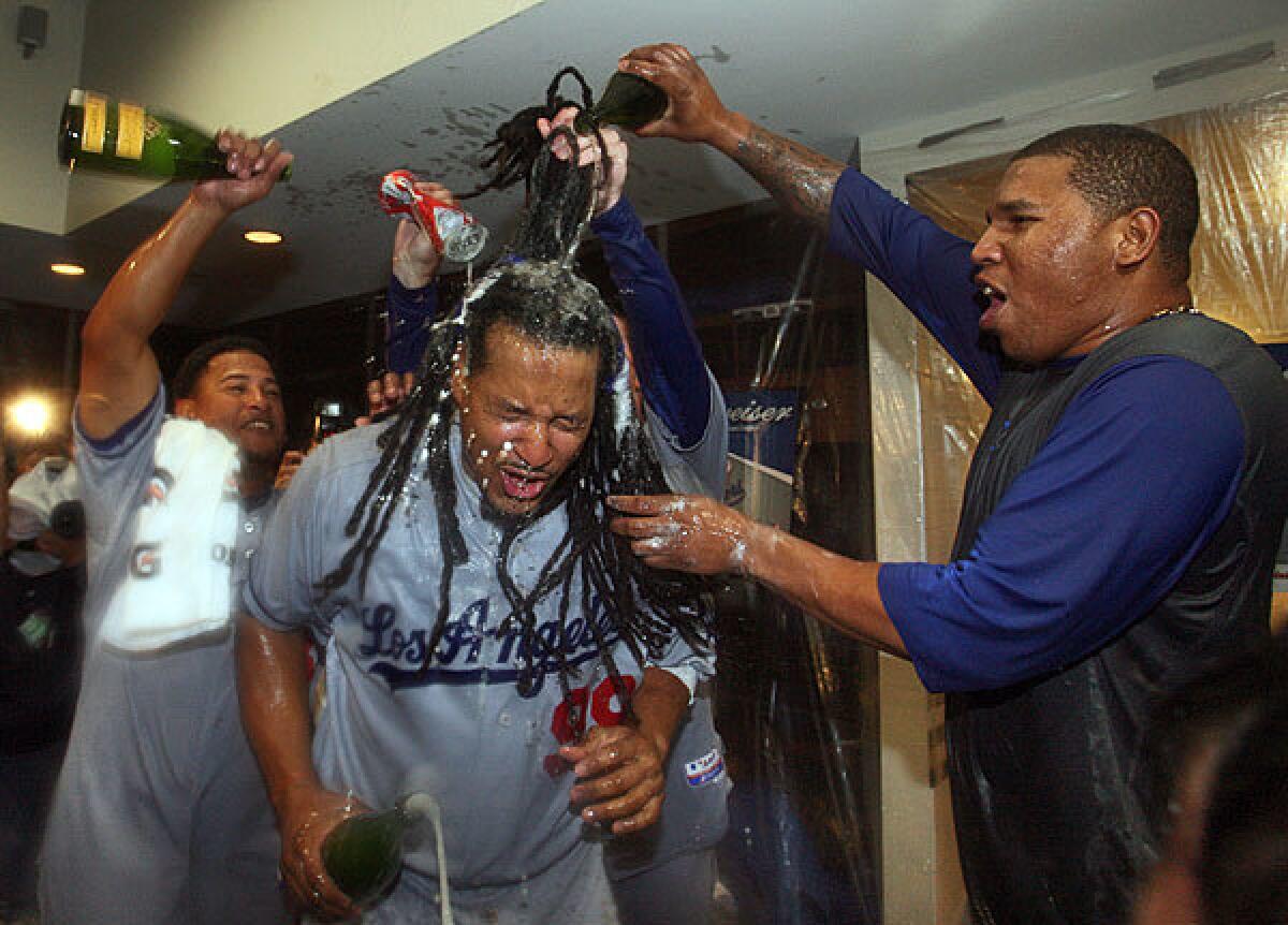 Dodgers left fielder Manny Ramirez gets doused by reliever Ronald Belisaro, right, and infielder Ronnie Belliard during the clubhouse celebration following a sweep of the St. Louis Cardinals in the National League division series on Saturday.