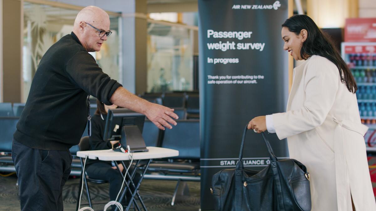 Passenger handing over bag for weighing at airline check-in