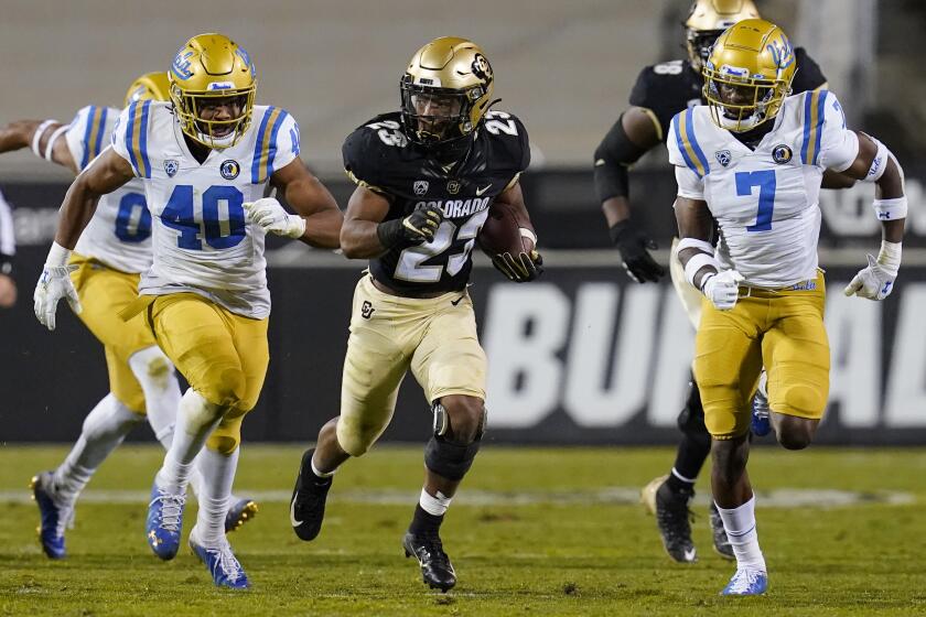 Colorado running back Jarek Broussard slips between UCLA linebacker Caleb Johnson and defensive back Mo Osling III.