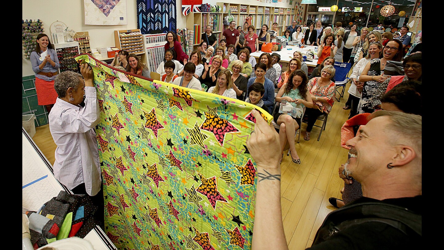 Quilting instructor Sylvia Q. Davis and Craig Wcislo display Davis' quilt "98% Off" during an LA Modern Quilt Guild meeting at Sew Modern in L.A.