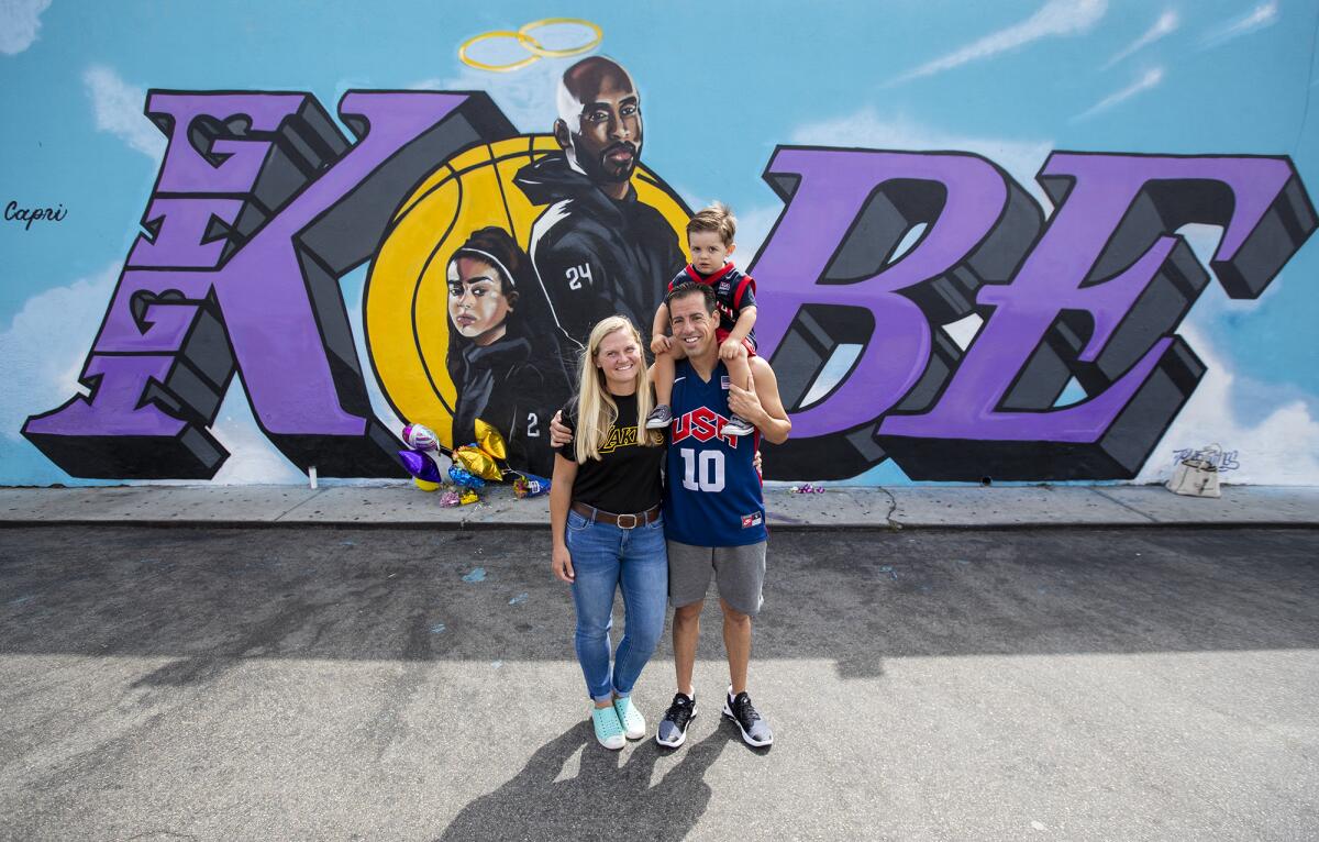 Ryan Broccolo with wife Megan and son Brayden pose for a photo in front of a Kobe Bryant mural.
