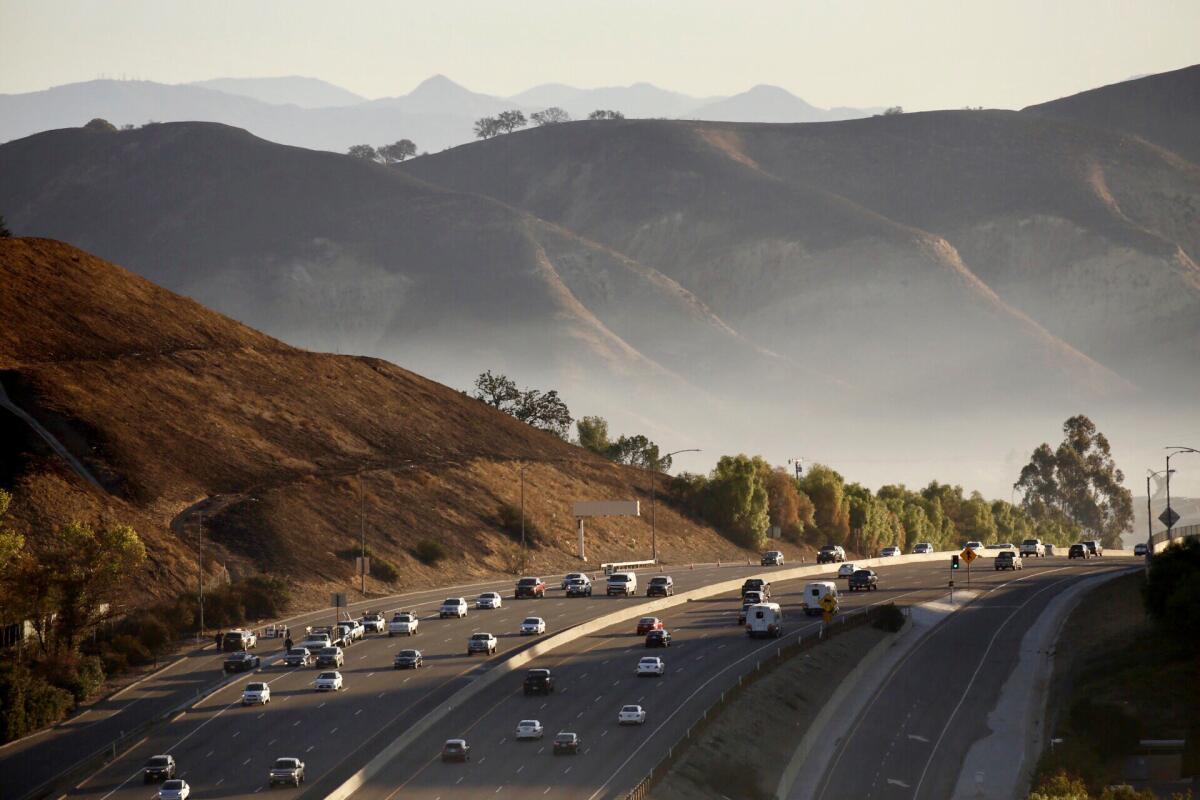 Smoke lingers as vehicles cruise past scorched hillsides between Calabasas and Agoura Hills on the 101 Freeway on Nov. 12.