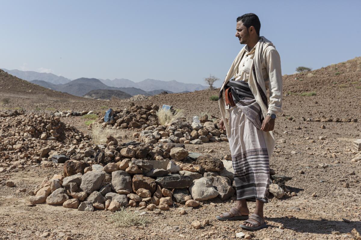 Ahmad Dabisi, who smuggles migrants from Yemen to Saudi Arabia, in a small cemetery where some of his clients lie buried.