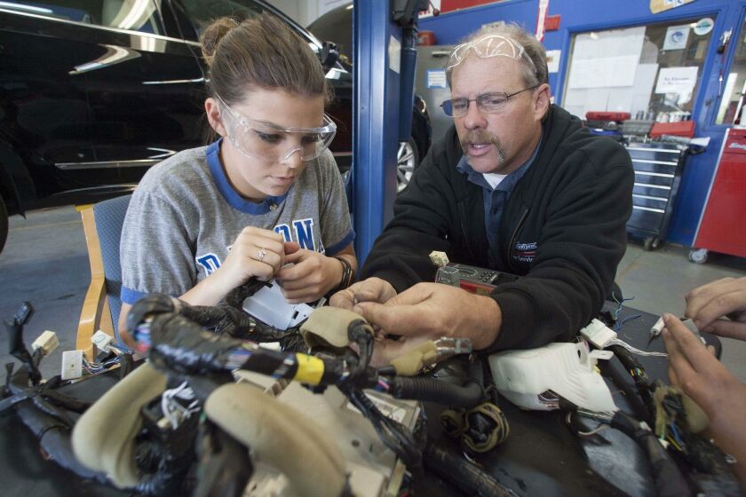 Auto mechanics teacher Robert Grace (right) assists student Alexia Hall as she practices for National Automotive Technology Challenge.