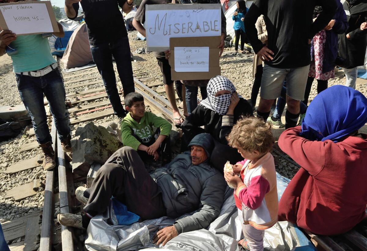 Migrants and refugees stay on train tracks as Greek police try to persuade them to leave the railroad in the makeshift camp at the Greek-Macedonian border near the village of Idomeni on April 18, 2016.