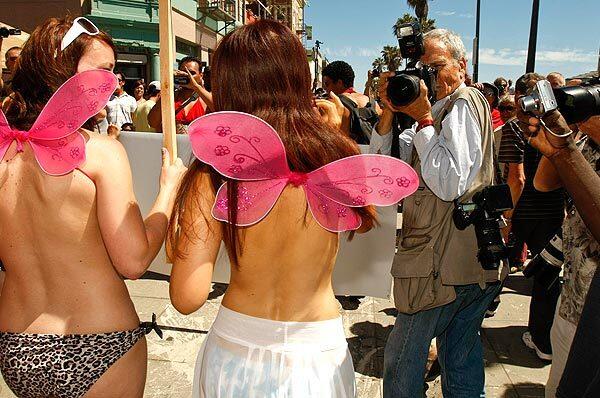 Passersby shoot photos as topless protesters march down the Venice Beach boardwalk in August 2010. Demonstrations were held on the same day in a dozen cities, urging equal rights for women to go topless in public.